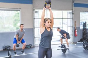 A lifter pressing dumbbells overhead after a squat in a thruster.