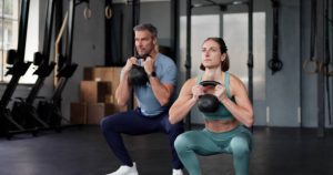 A beginner performing a dumbbell squat in a home gym.