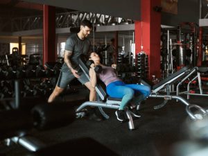 A beginner performing a dumbbell bench press on a flat bench.