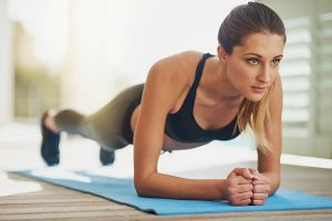 A person holding a plank while performing dumbbell rows.