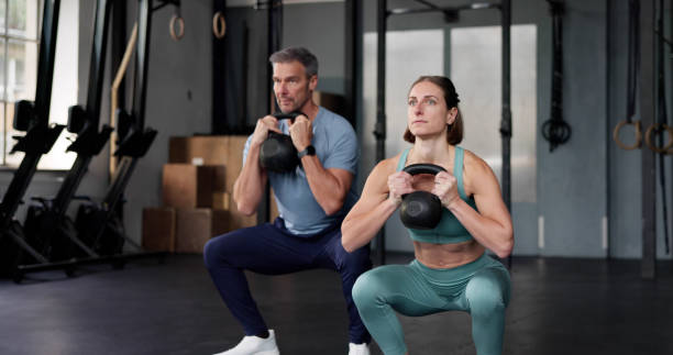 A beginner performing a dumbbell squat in a home gym.